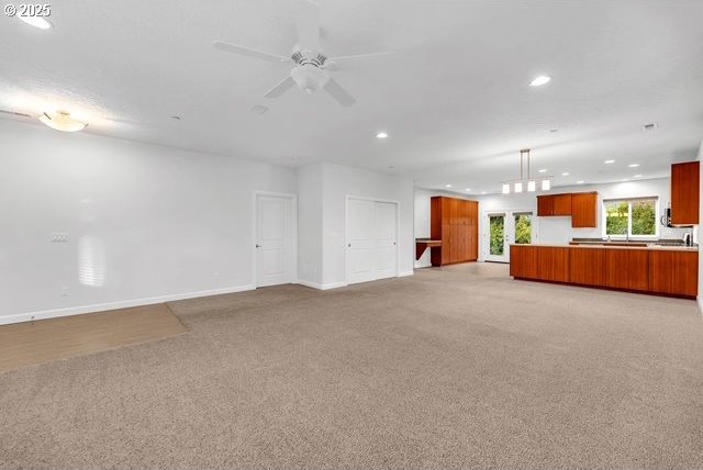 unfurnished living room with ceiling fan and light colored carpet