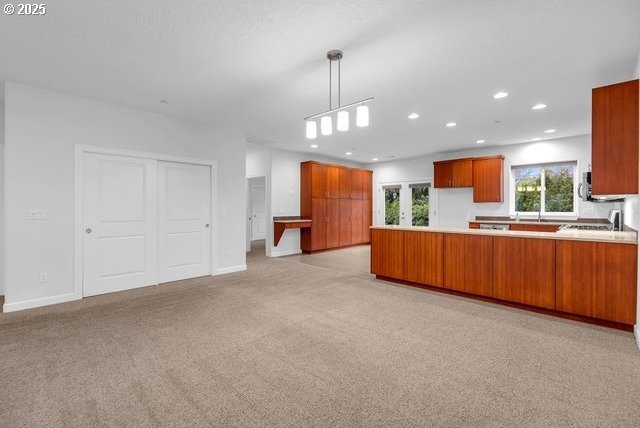 kitchen featuring pendant lighting, light colored carpet, and kitchen peninsula