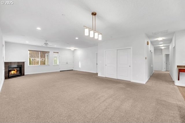 unfurnished living room featuring ceiling fan, light colored carpet, and a fireplace