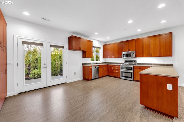 kitchen with french doors, stainless steel appliances, sink, and light hardwood / wood-style floors