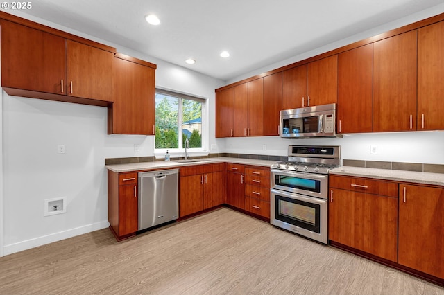 kitchen with stainless steel appliances, sink, and light wood-type flooring