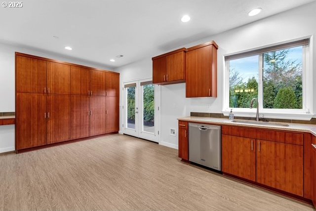 kitchen featuring stainless steel dishwasher, sink, and light hardwood / wood-style flooring