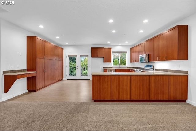 kitchen featuring light colored carpet, stainless steel appliances, kitchen peninsula, and french doors