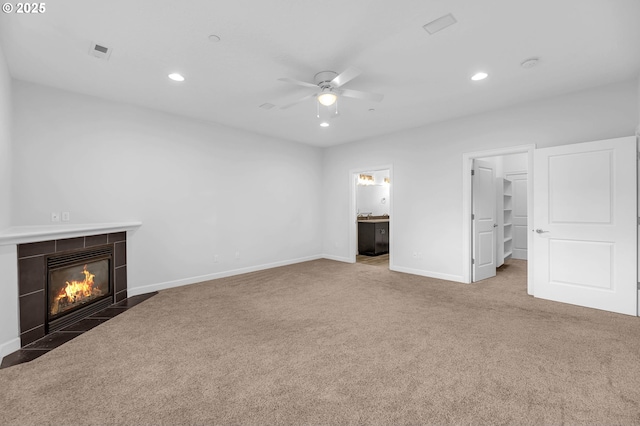 unfurnished living room with ceiling fan, a tile fireplace, and carpet