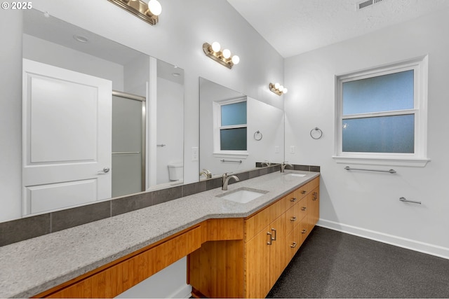 bathroom featuring vanity, a shower with door, and toilet