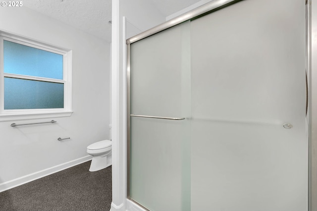 bathroom featuring a textured ceiling, toilet, and walk in shower