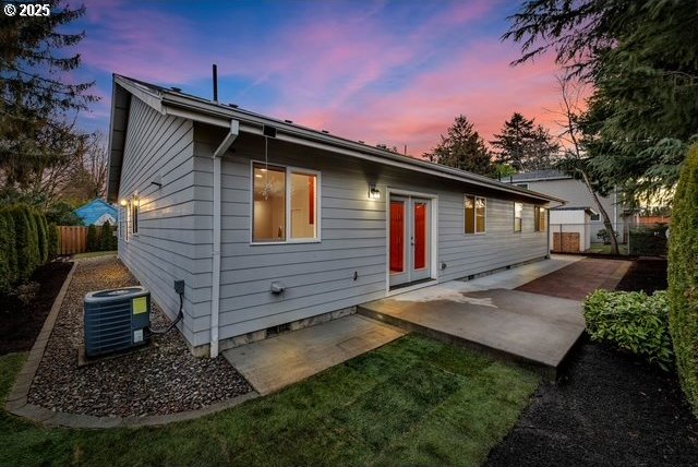 back house at dusk featuring cooling unit and a patio area