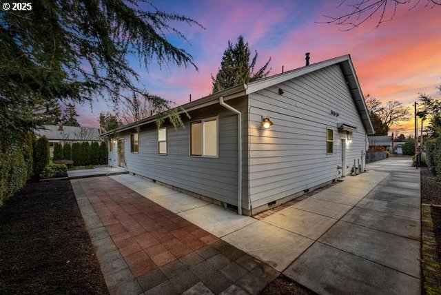 property exterior at dusk featuring a patio area