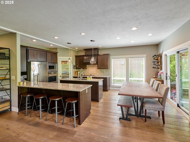 kitchen featuring light wood-style floors, appliances with stainless steel finishes, a peninsula, and a textured ceiling
