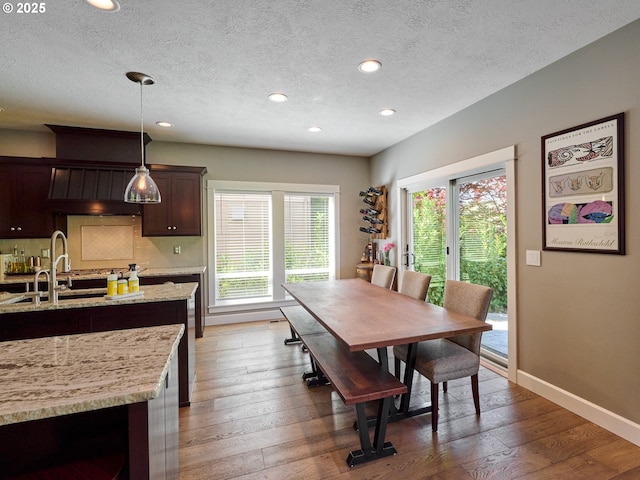 dining space with recessed lighting, a textured ceiling, wood-type flooring, and baseboards