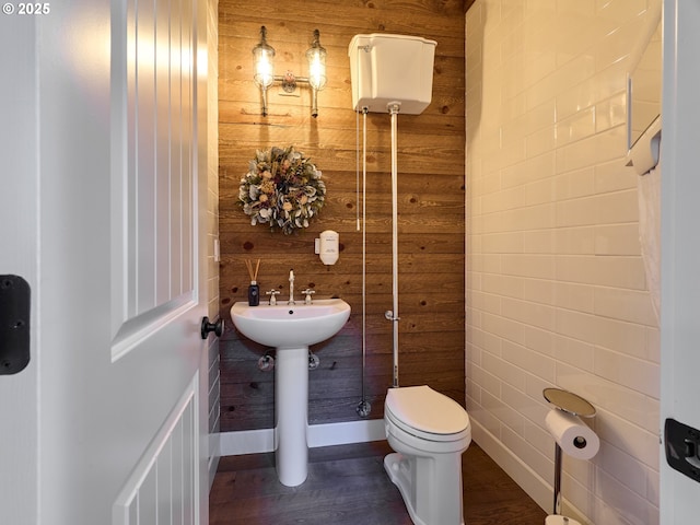 bathroom featuring wood finished floors, wooden walls, and toilet