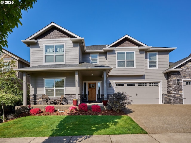 craftsman-style house featuring a front lawn, stone siding, a garage, a porch, and driveway