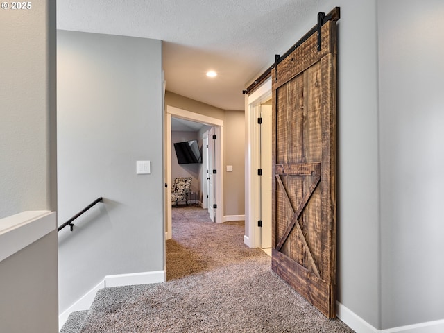 hall with baseboards, recessed lighting, a barn door, a textured ceiling, and carpet