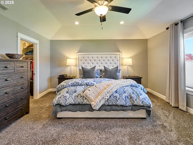 bedroom featuring a walk in closet, visible vents, baseboards, lofted ceiling, and carpet flooring