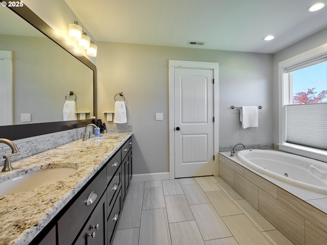 full bathroom with a sink, baseboards, a whirlpool tub, and visible vents