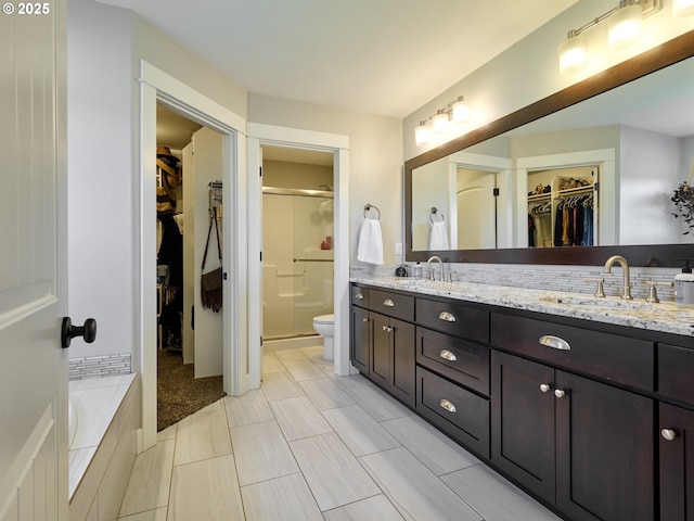 bathroom featuring double vanity, a sink, a walk in closet, and a shower stall