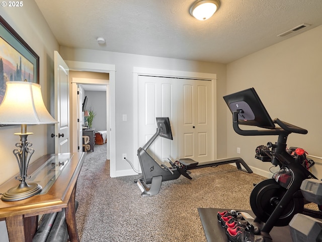 workout area featuring carpet flooring, a textured ceiling, visible vents, and baseboards