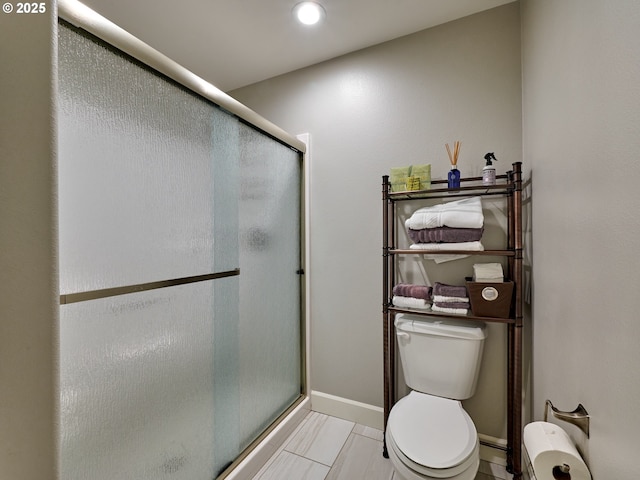 full bathroom with baseboards, a shower stall, and toilet