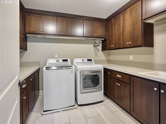 clothes washing area featuring light tile patterned floors, independent washer and dryer, and cabinet space