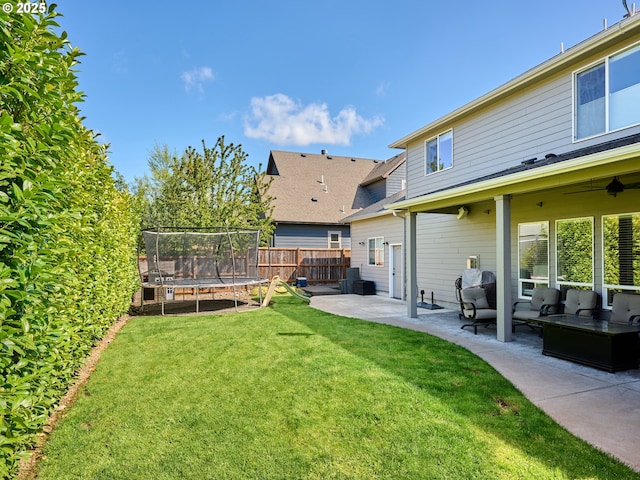 view of yard featuring fence, a trampoline, outdoor lounge area, a patio area, and a ceiling fan