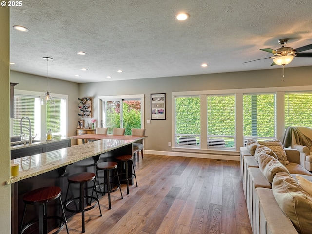 kitchen featuring a textured ceiling, open floor plan, a sink, and hardwood / wood-style flooring