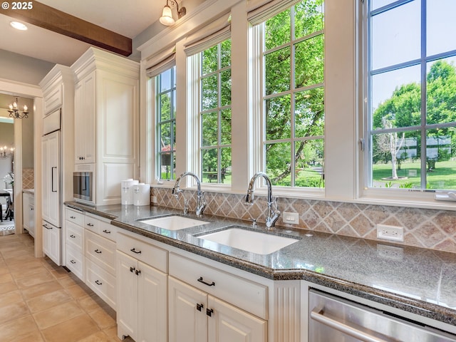 kitchen with backsplash, beam ceiling, stainless steel appliances, a notable chandelier, and white cabinets