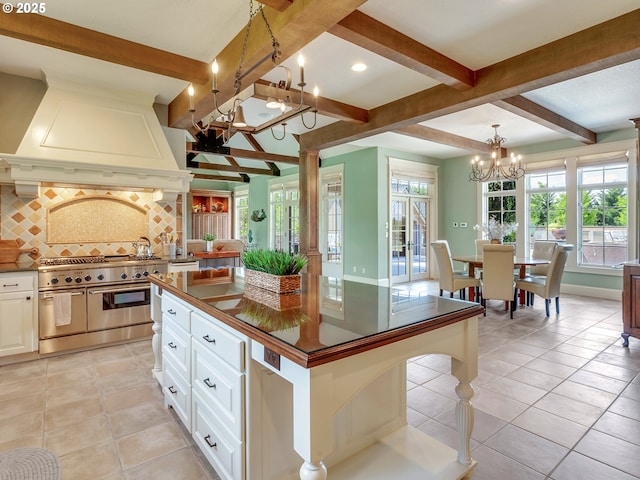 kitchen featuring tasteful backsplash, white cabinets, a kitchen island, custom exhaust hood, and range with two ovens