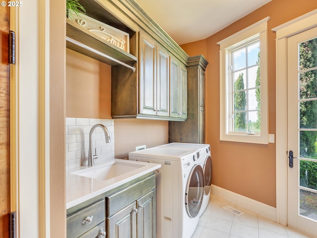 clothes washing area featuring cabinets, sink, light tile patterned floors, and washing machine and clothes dryer