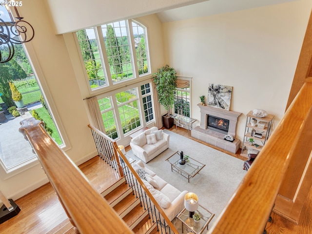 living room featuring a fireplace, a towering ceiling, plenty of natural light, and light hardwood / wood-style floors