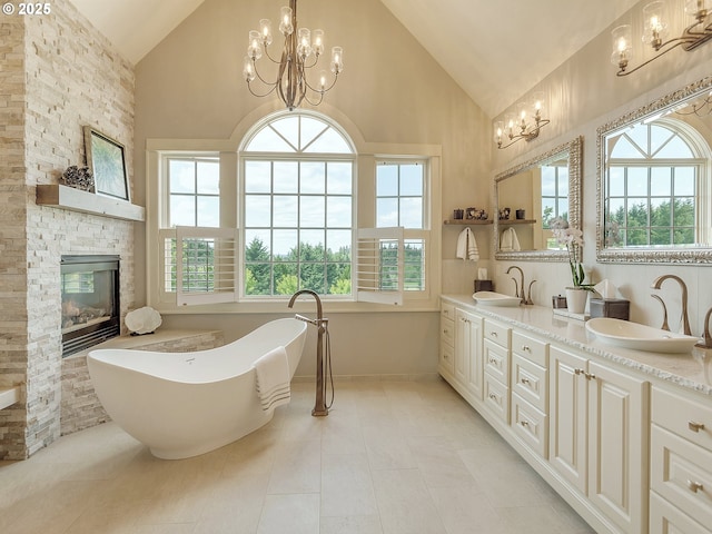 bathroom with a wealth of natural light, a fireplace, a chandelier, a tub to relax in, and vanity