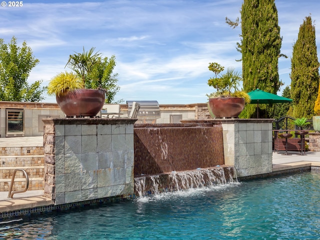 view of swimming pool with a grill, pool water feature, area for grilling, and a patio