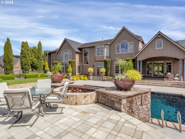 rear view of property featuring french doors, a patio, and an outdoor fire pit