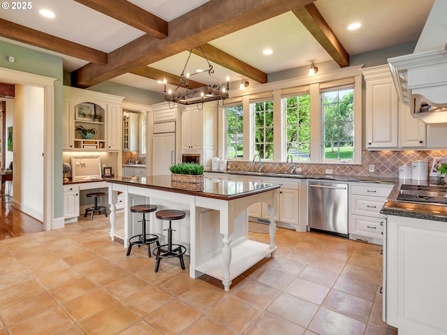 kitchen with a breakfast bar, a center island, built in desk, stainless steel appliances, and decorative backsplash