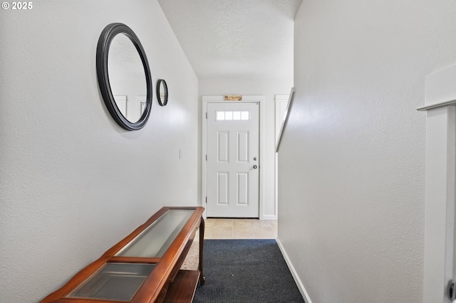 doorway to outside with a textured wall, baseboards, carpet floors, and a textured ceiling