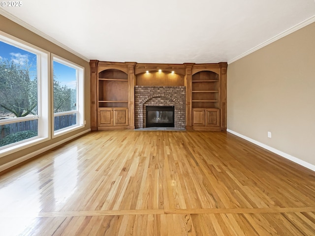 unfurnished living room with baseboards, crown molding, light wood-type flooring, a brick fireplace, and built in shelves