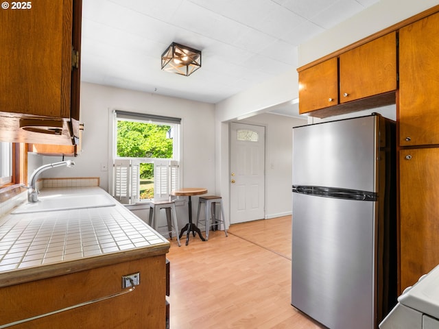 3128 SE 64th Ave, Portland, OR 97206 - kitchen with freestanding refrigerator, a sink, tile countertops, and brown cabinets