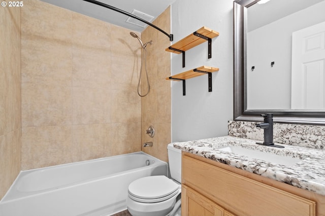 full bathroom featuring vanity, tiled shower / bath combo, and toilet