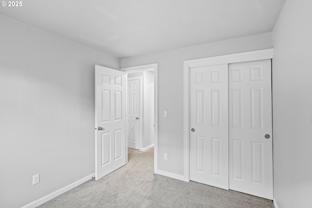 unfurnished bedroom featuring light carpet and a closet