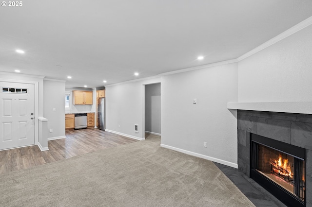 unfurnished living room featuring crown molding, a tile fireplace, and dark colored carpet