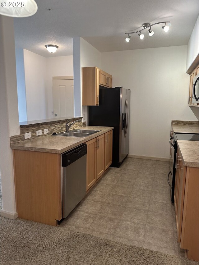 kitchen with kitchen peninsula, sink, light brown cabinetry, and stainless steel appliances