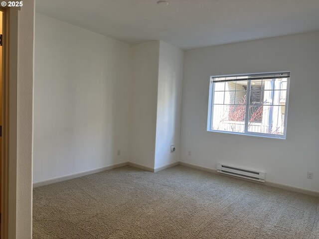 carpeted spare room with a baseboard heating unit