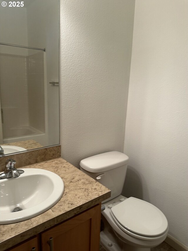 bathroom with toilet, walk in shower, and vanity