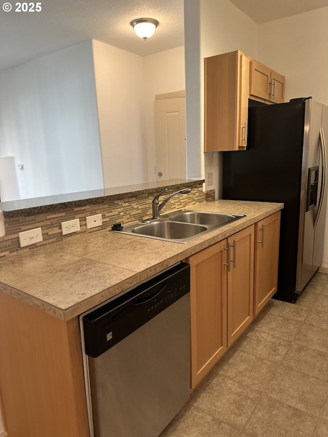 kitchen with kitchen peninsula, appliances with stainless steel finishes, sink, and light brown cabinets