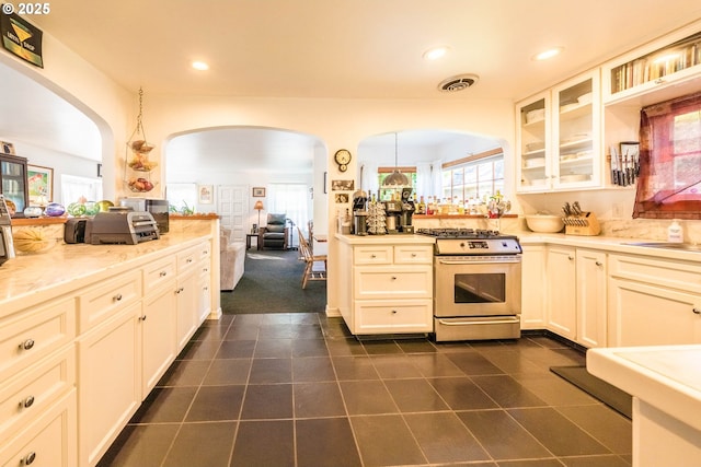 1756 NW 35th Pl, Lincoln City, OR 97367 - kitchen with stainless steel gas stove, arched walkways, dark tile patterned floors, glass insert cabinets, and recessed lighting