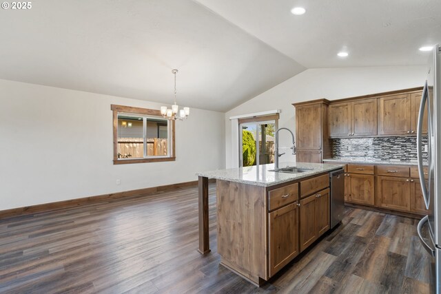 kitchen with a sink, stainless steel appliances, vaulted ceiling, dark wood-style floors, and light stone counters