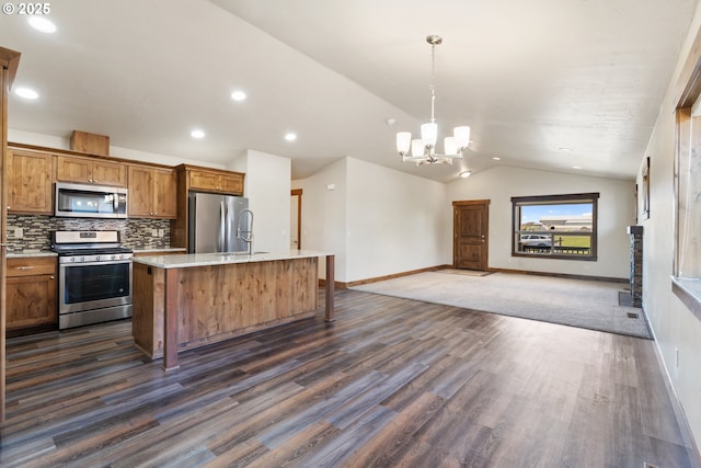 kitchen with appliances with stainless steel finishes, lofted ceiling, baseboards, a sink, and open floor plan