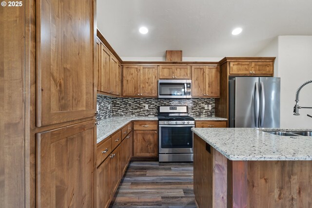 kitchen with stainless steel appliances, a sink, dark wood finished floors, brown cabinets, and recessed lighting