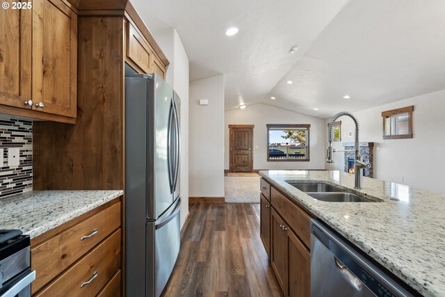 kitchen with stainless steel appliances, a sink, tasteful backsplash, vaulted ceiling, and dark wood finished floors