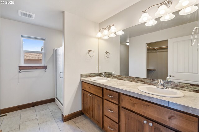 full bathroom featuring baseboards, double vanity, a stall shower, and tile patterned floors