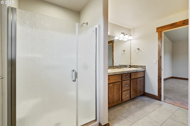 bathroom featuring a stall shower, double vanity, tile patterned flooring, and baseboards